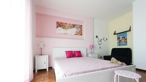 A bedroom with a bed, nightstands, a chair, and artwork on the walls. - Casa Vacanza Santa Laura (Sperlonga)