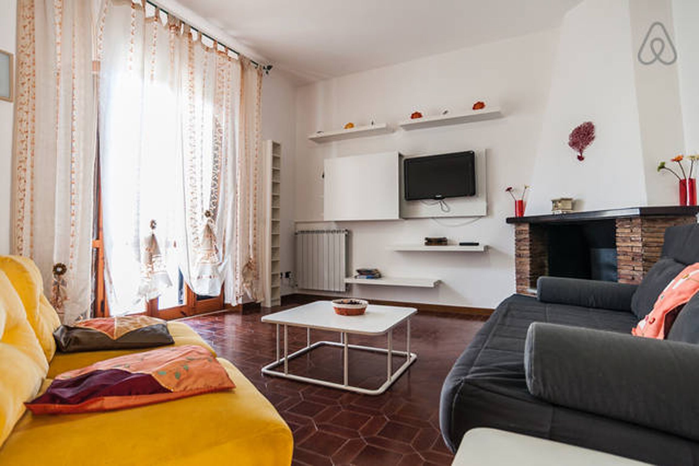 A living room with a sofa, a coffee table, a television mounted on the wall, and a fireplace.