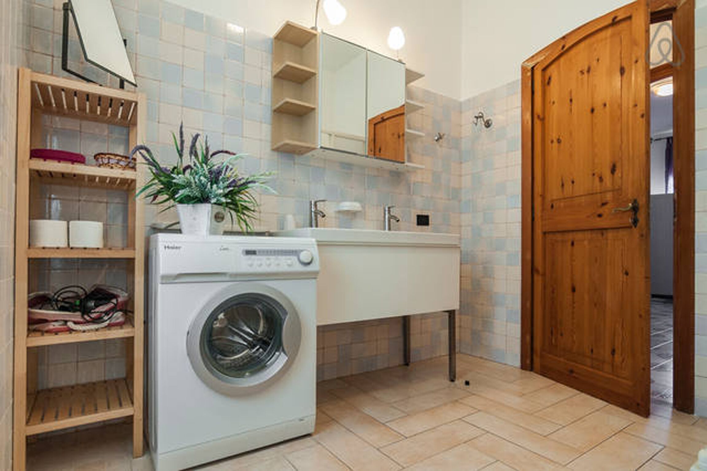 Un baño pequeño con lavadora, un lavamanos, un espejo y una puerta de madera.