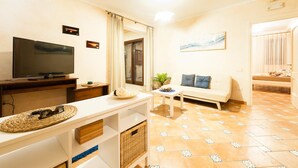 A living room with a flat-screen TV, a sofa, a coffee table, and a TV stand. - Casa Vacanza Villa Polifemo (Sperlonga)