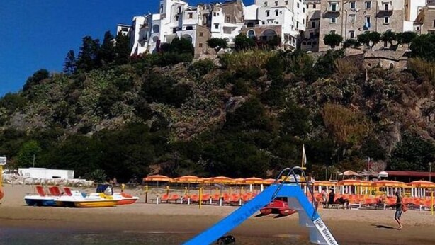 A boat on a beach with a building in the background. - Casa Vacanza Colombo (Sperlonga)