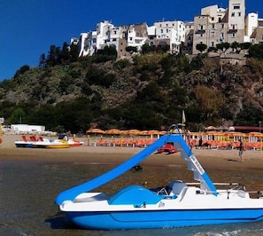 A boat on a beach with a building in the background. - Casa Vacanza Colombo (Sperlonga)