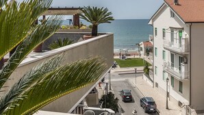 A coastal building with balconies overlooking the sea, a paved street, and parked cars. - Casa Vacanza Colombo (Sperlonga)