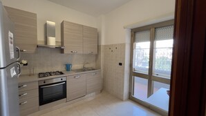 A modern kitchen with a gas stove, oven, and stainless steel refrigerator. There is a window with a view of the outside. - Casa Vacanza Colombo (Sperlonga)