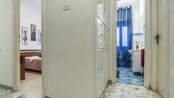 Un pasillo con una cama, un armario y un baño visible a través de una puerta abierta.