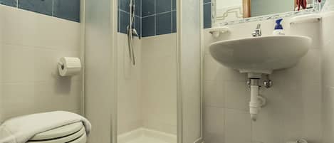 A bathroom with a toilet, a shower, and a sink.