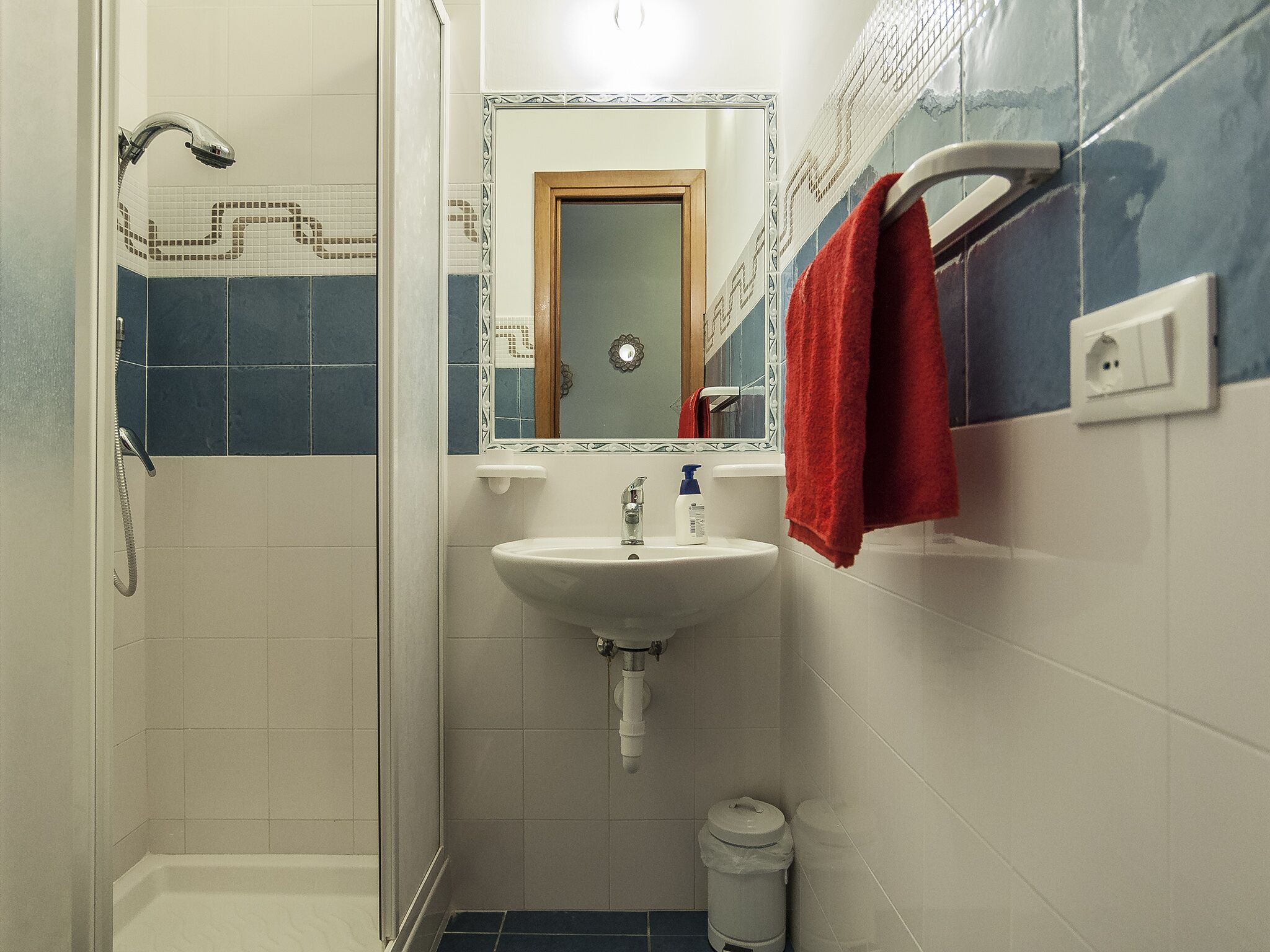 Ein Badezimmer mit Dusche, Waschbecken und Spiegel.