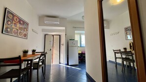 A modern kitchen with a refrigerator, a dining table with chairs, and a potted plant. - Casa Vacanza Vespucci 4 (Sperlonga)