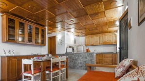 A cozy kitchen with wooden cabinets, a dining table with chairs, and a bench. - Casa Vacanza Nikita (Sperlonga)