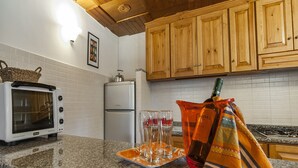 A kitchen with wooden cabinets, a microwave, a refrigerator, and a granite countertop. - Casa Vacanza Nikita (Sperlonga)
