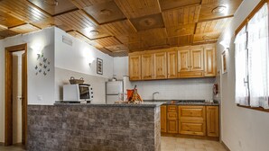 A kitchen with wooden cabinets, a stone island, and a wooden ceiling. - Casa Vacanza Nikita (Sperlonga)