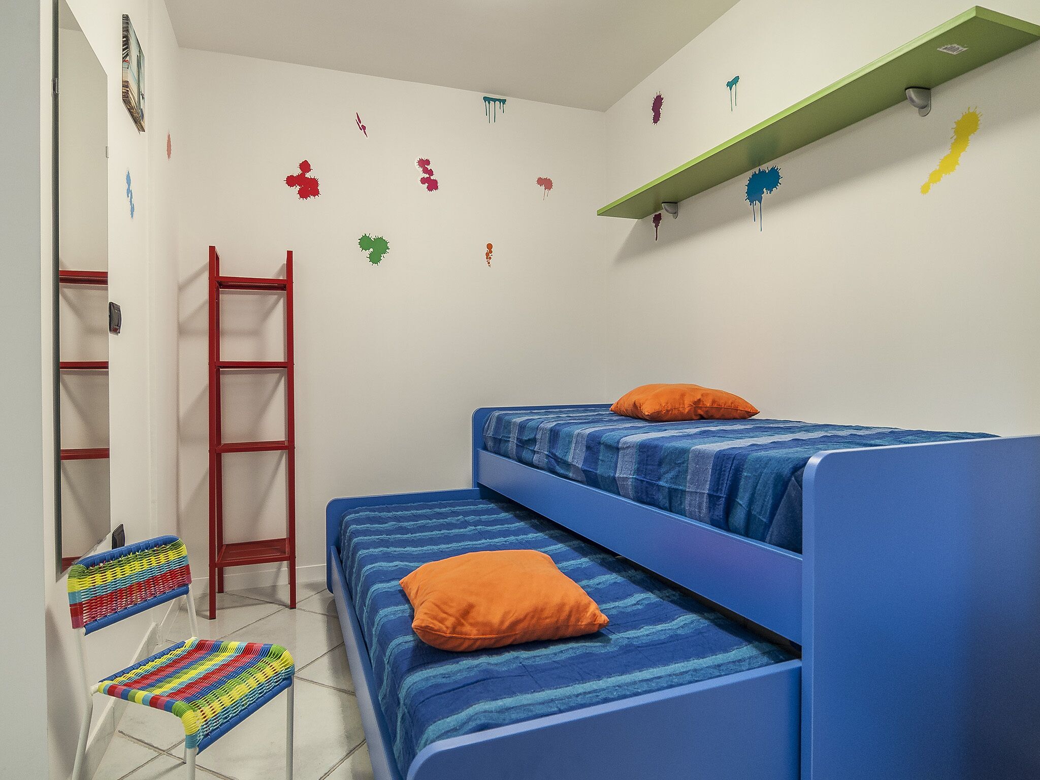 A room with a bunk bed, a chair, a ladder, and wall decorations.