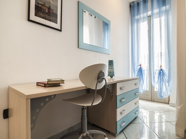 A modern room with a desk, chair, and a window with curtains.