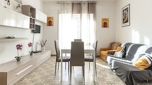 A modern living room with a dining table, chairs, a sofa, and a TV. - Casa Vacanza Scilla (Sperlonga)