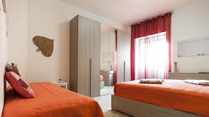 A hotel room with two beds, a wardrobe, a mirror, and a window with curtains. - Casa Vacanza Scilla (Sperlonga)