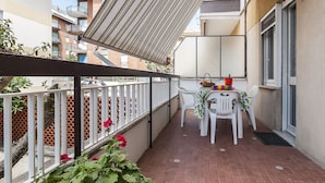 A balcony with a table set for two, a chair, and a potted plant with red flowers. - Casa Vacanza Scilla (Sperlonga)