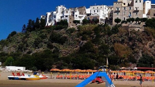 A boat on a beach with a building in the background. - Casa Vacanza Cariddi Loft (Sperlonga)