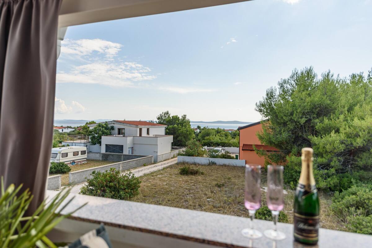 Un balcón con vistas a una zona residencial, una botella de champán y dos copas de vino.