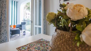 A room with a view of a balcony, a wicker basket with flowers, and a patterned table runner. - Casa Vacanza Mare Verde (Sperlonga)