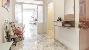 A spacious hallway with a marble floor, a dining area with chairs and a table, and a kitchen area with a countertop and a bowl. - Casa Vacanza Flora (Sperlonga)