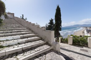 A stone staircase leading down to a beach with a view of the ocean and mountains in the distance. - Casa Vacanza Madonnella 10 (Sperlonga)
