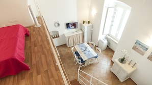 A small, well-lit room with a bed, a dining table, and a TV. - Casa Vacanza Madonnella 12 (Sperlonga)