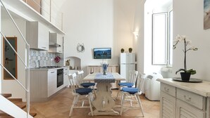 A modern kitchen with a dining area, featuring a tiled backsplash, a built-in oven, and a dining table with chairs. - Casa Vacanza Madonnella 12 (Sperlonga)