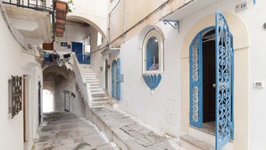 A narrow stone-paved alleyway with a staircase leading to a building with blue doors and windows. - Casa Vacanza Madonnella 12 (Sperlonga)