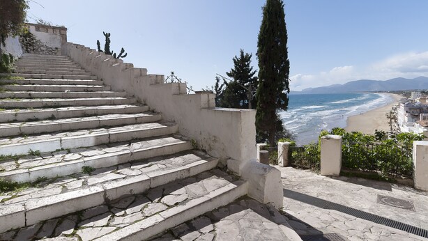 A stone staircase leading down to a beach with a view of the ocean and mountains in the distance. - Casa Vacanza Madonnella 12 (Sperlonga)