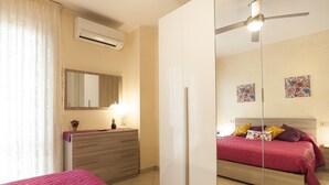 Een slaapkamer met een bed, een dressoir, een spiegel en een airconditioning.