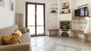 Een woonkamer met een bank, een televisie en een open haard.
