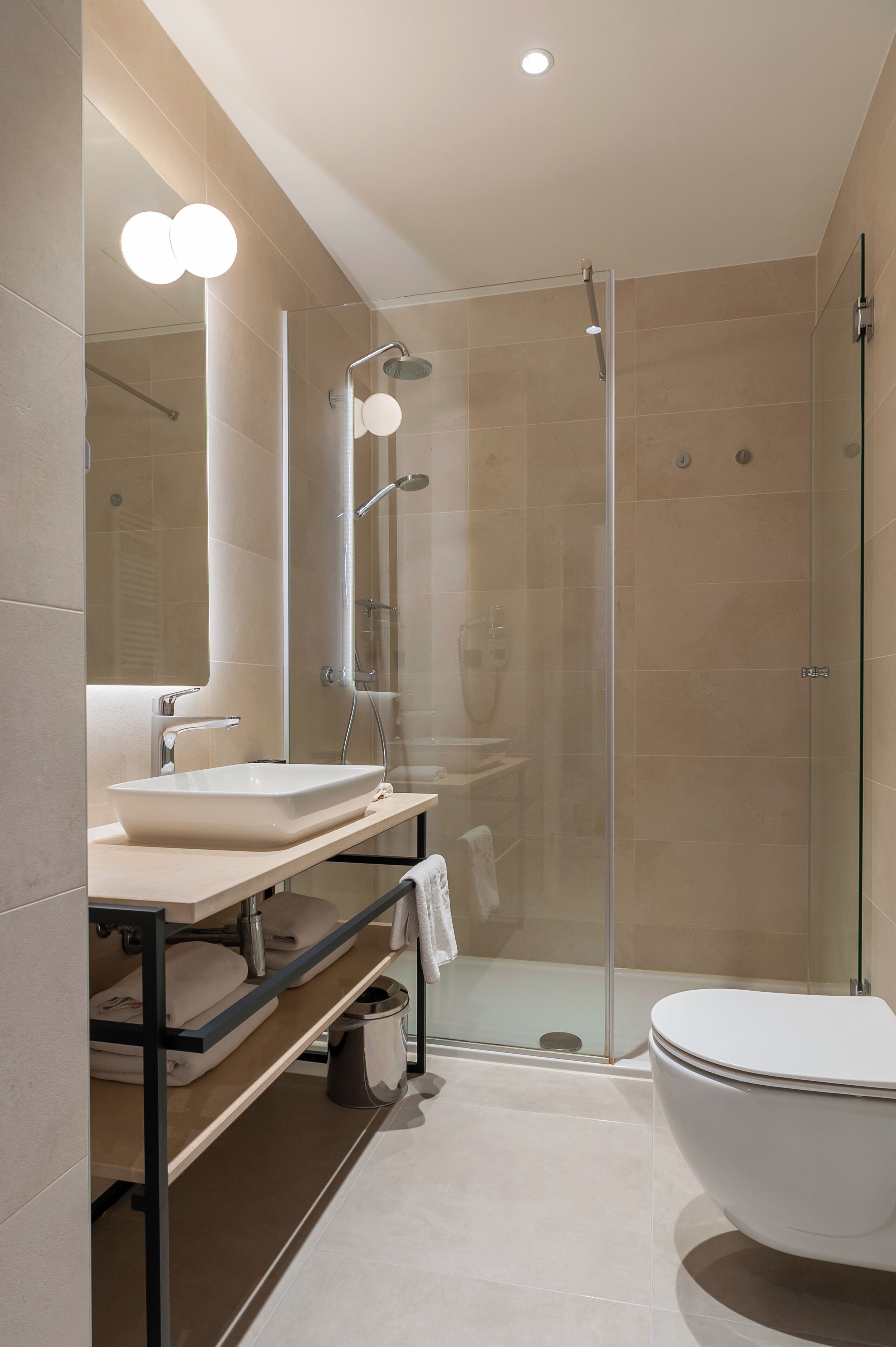 A modern bathroom with a glass-enclosed shower, a white sink, and a large bathtub.