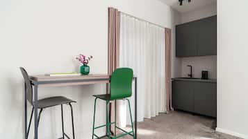 Una kitchenette pequeña con un armario oscuro, una sola silla y un escritorio con un florero.