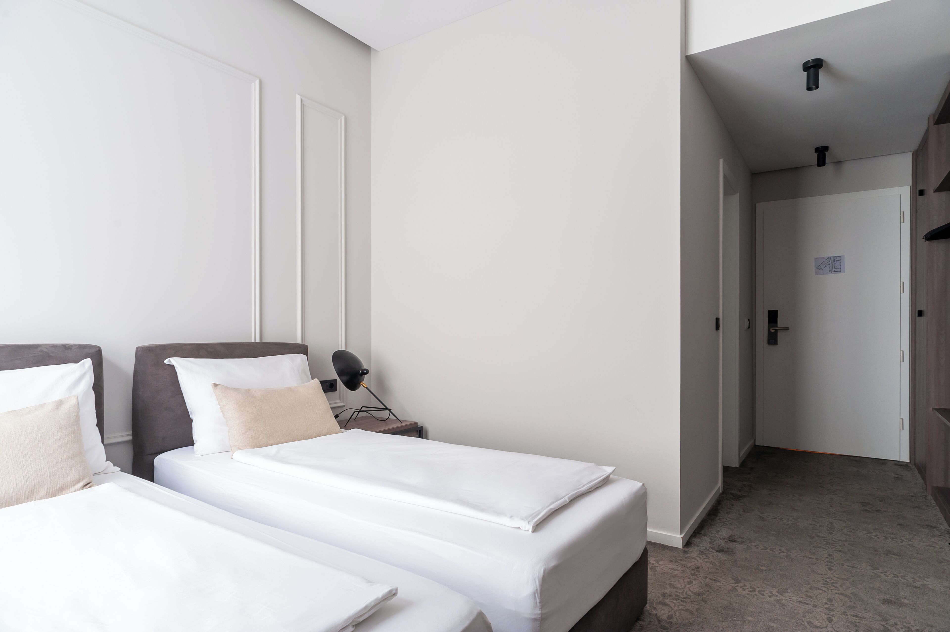 A hotel room with two beds, a nightstand, a desk, and a wardrobe.
