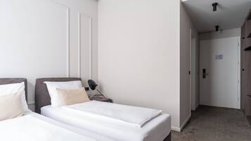 A hotel room with two beds, a nightstand, a desk, and a wardrobe.