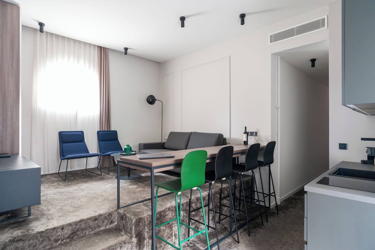 Un espacio habitable moderno y compacto con comedor, sofá y zona de cocina.