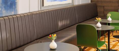 A modern waiting area with a leather bench, green chairs, and a patterned floor.
