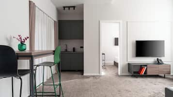 Una sala de estar moderna con televisor de pantalla plana, una mesa de centro y un comedor con una mesa de madera y dos sillas.
