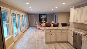 Una cocina amplia con una isla grande, suelo de madera y armarios blancos.