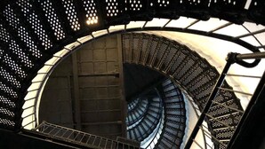 Una escalera de caracol con barandillas de metal y un cerramiento de vidrio.