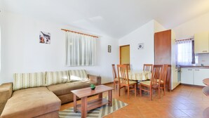 A living room with a sofa, a coffee table, and a dining area with chairs and a table. - Apartement Delac (Vir)