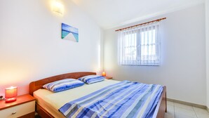 A bedroom with a bed, bedside lamps, a nightstand, a window with curtains, and a wall-mounted light fixture. - Apartement Delac (Vir)