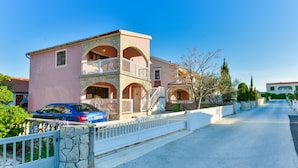 A two-story building with a balcony, a stone wall, and a blue car parked in front. - Apartement Delac (Vir)