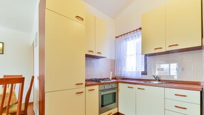 A kitchen with white cabinets, a stove, and a sink. - Apartement Delac (Vir)