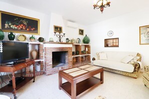 Una sala de estar con chimenea de ladrillo, un televisor sobre un mueble de madera, un sofá y una mesa de centro.
