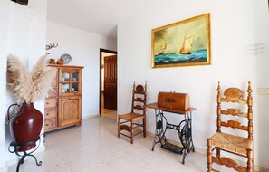 A room with a wooden cabinet, a sewing machine, and a chair.
