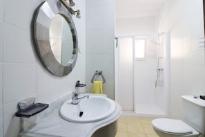 Un bagno con lavandino, specchio e water bianchi.