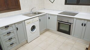 Une cuisine de taille réduite équipée d’un lave-linge, d’un four et de deux éviers.