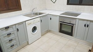 A compact kitchen with a washing machine, oven, and two sinks. - 1146 Villa Hermoso (Nerja)