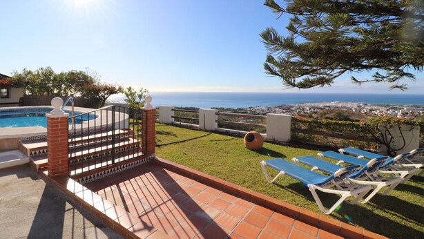 Une terrasse avec piscine, vue sur la mer et chaises longues.